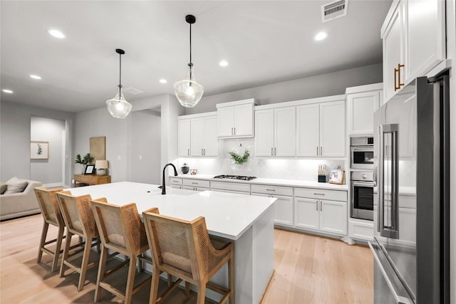 kitchen featuring high quality fridge, a sink, visible vents, light wood-type flooring, and backsplash