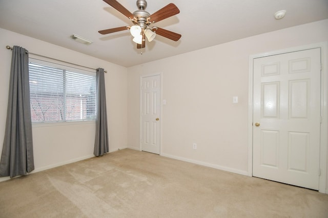 empty room with a ceiling fan, visible vents, light carpet, and baseboards