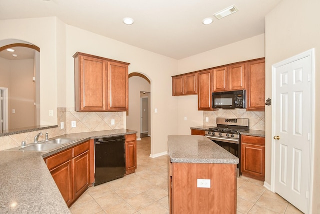 kitchen featuring visible vents, arched walkways, a kitchen island, black appliances, and a sink