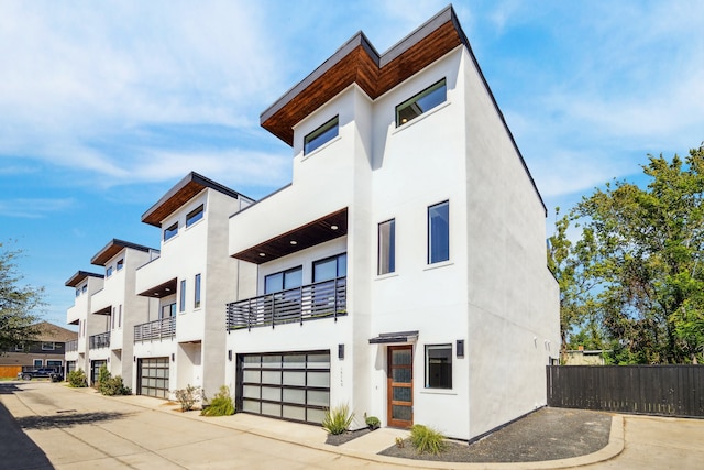 exterior space featuring a garage, fence, and stucco siding