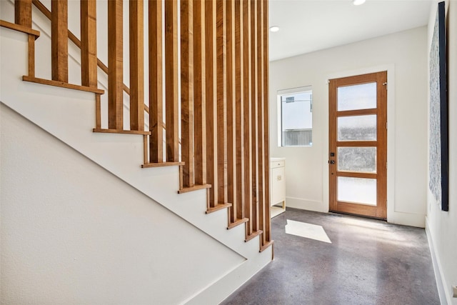 foyer with concrete flooring, recessed lighting, stairway, and baseboards