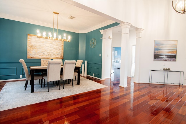 dining area featuring visible vents, dark wood-type flooring, ornamental molding, a decorative wall, and ornate columns