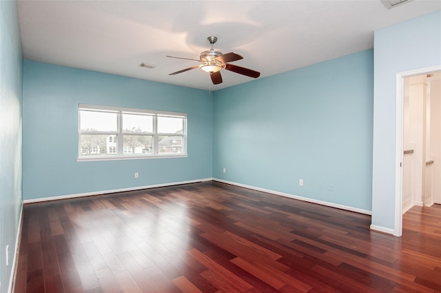 spare room featuring visible vents, baseboards, a ceiling fan, and dark wood-style flooring