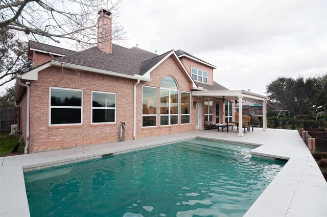 rear view of house featuring a fenced in pool, brick siding, and a patio area