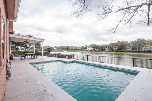 view of swimming pool with a water view, a patio, fence, a fenced in pool, and ceiling fan