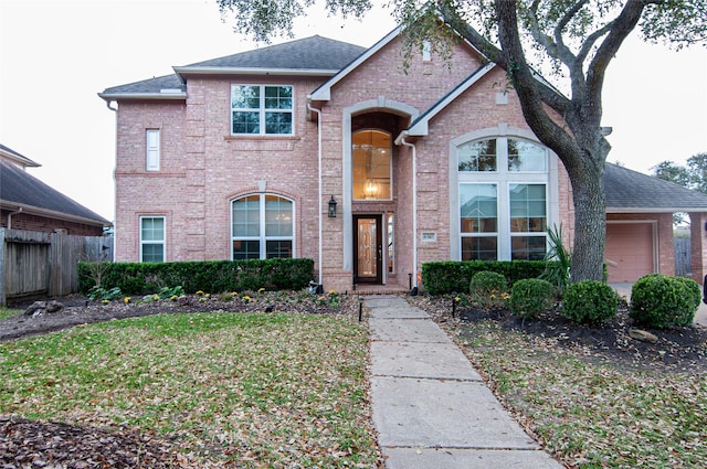 traditional home with brick siding, a shingled roof, and fence