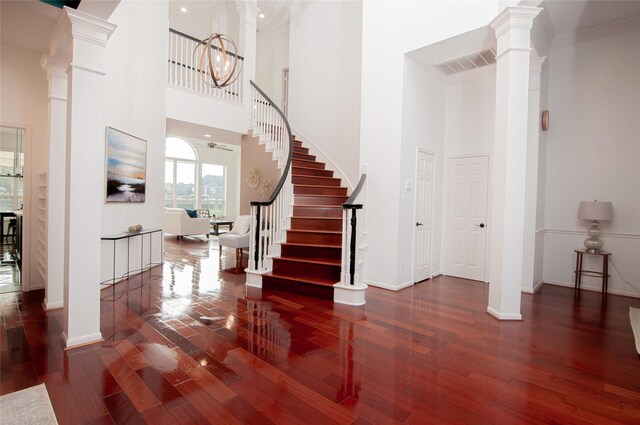 entryway with visible vents, wood finished floors, stairs, and decorative columns