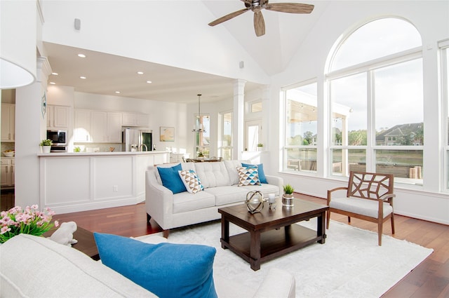 living room featuring decorative columns, recessed lighting, light wood-style floors, high vaulted ceiling, and a ceiling fan