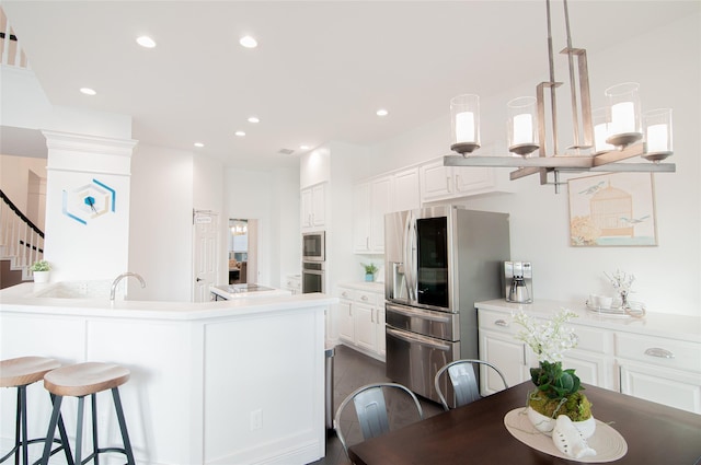 kitchen with a breakfast bar, recessed lighting, stainless steel appliances, a peninsula, and white cabinets