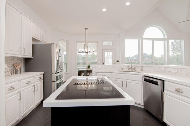 kitchen featuring a sink, a center island, white cabinetry, stainless steel appliances, and decorative backsplash