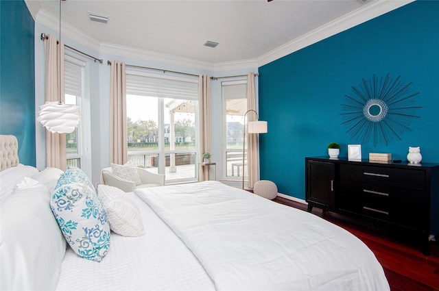 bedroom with visible vents, ornamental molding, an accent wall, and wood finished floors