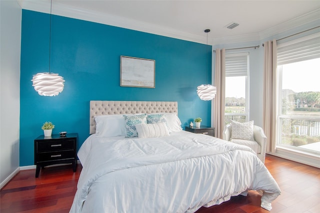 bedroom featuring baseboards, wood finished floors, visible vents, and ornamental molding