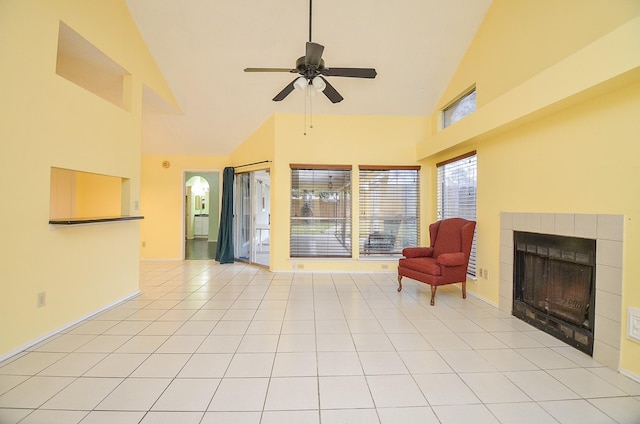 living area featuring light tile patterned floors, baseboards, a ceiling fan, a tiled fireplace, and high vaulted ceiling