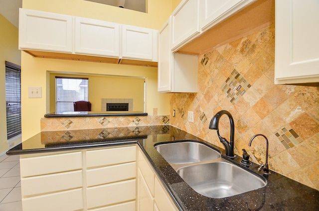 kitchen with dark stone counters, white cabinets, a sink, and decorative backsplash