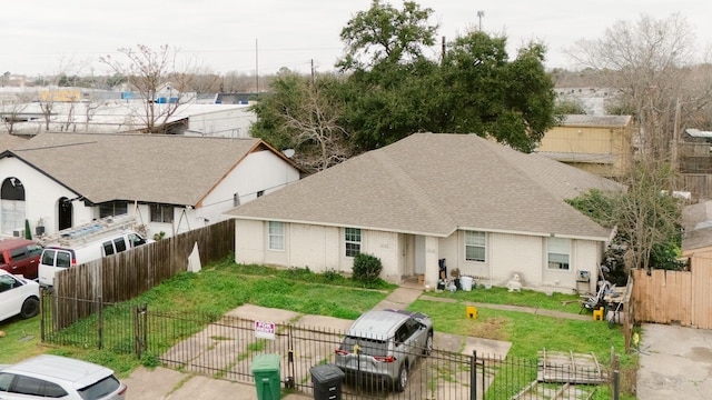 exterior space with fence private yard, roof with shingles, a residential view, and brick siding