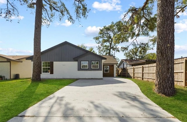 view of front facade featuring concrete driveway, brick siding, a front yard, and fence