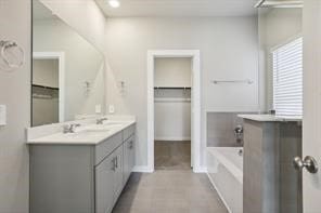 full bathroom featuring a garden tub, a sink, a spacious closet, and double vanity