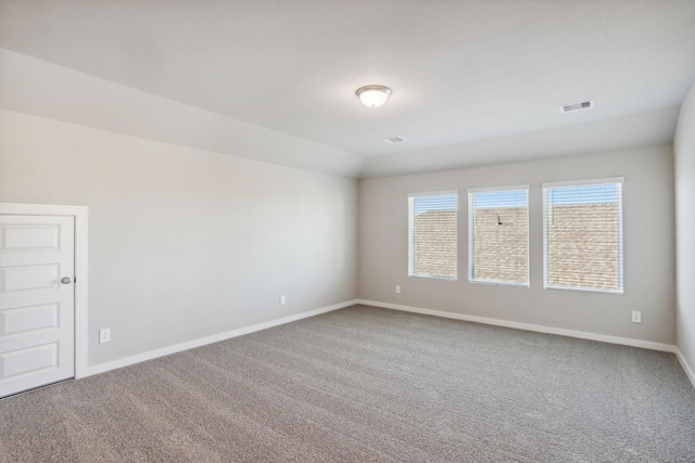 carpeted spare room featuring lofted ceiling, visible vents, and baseboards