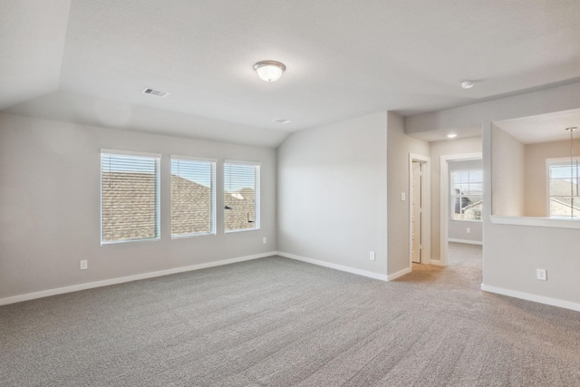 empty room featuring lofted ceiling, carpet flooring, and baseboards