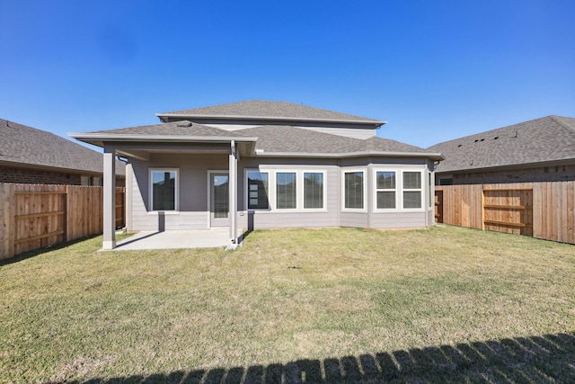 rear view of property featuring a patio, a yard, and a fenced backyard