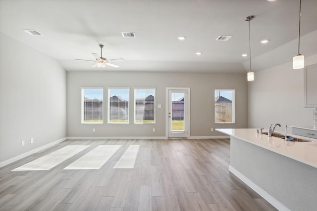 interior space with light wood finished floors, a sink, visible vents, and baseboards