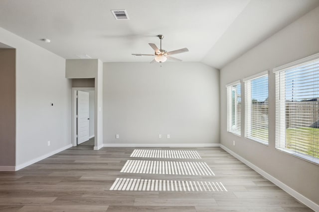 spare room featuring lofted ceiling, a ceiling fan, light wood-style floors, visible vents, and baseboards