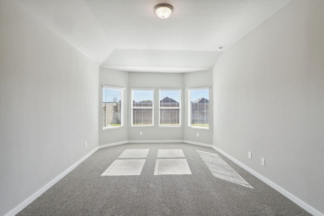 carpeted spare room with vaulted ceiling and baseboards