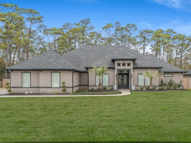 prairie-style home featuring roof with shingles, a front yard, and stucco siding