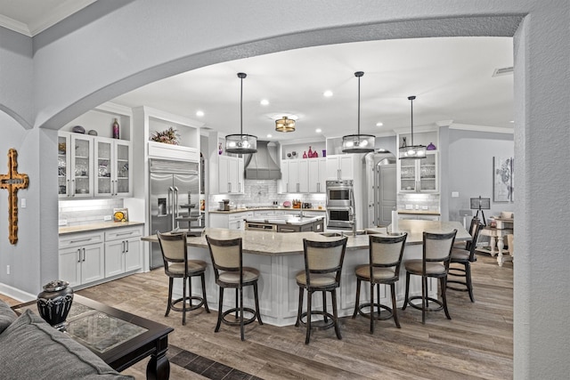 kitchen featuring a spacious island, appliances with stainless steel finishes, custom exhaust hood, white cabinetry, and pendant lighting