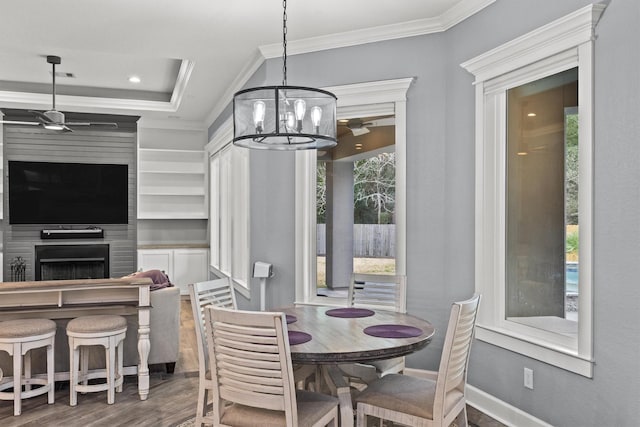 dining space featuring a large fireplace, baseboards, dark wood-style floors, and ornamental molding