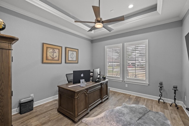 office area with light wood-style flooring, a tray ceiling, baseboards, and ornamental molding