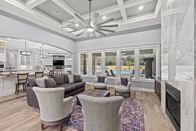 living area featuring visible vents, a premium fireplace, arched walkways, and a towering ceiling