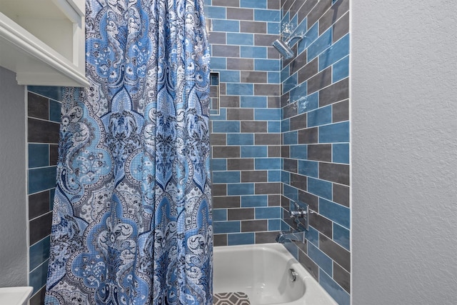 full bathroom with shower / tub combo and a textured wall