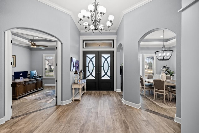 foyer entrance with a healthy amount of sunlight, light wood-style floors, baseboards, and arched walkways