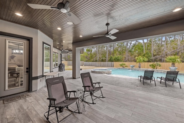 exterior space with a ceiling fan, a fenced backyard, and an in ground hot tub