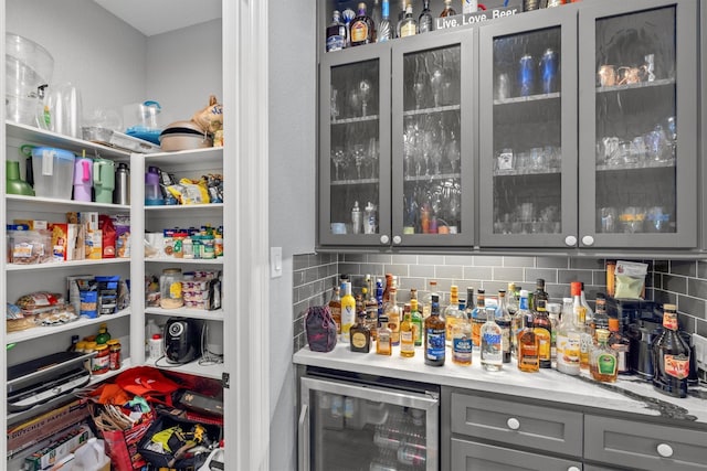 bar with tasteful backsplash, beverage cooler, and a bar