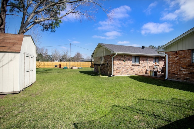 view of yard featuring a fenced backyard, a storage unit, and an outbuilding