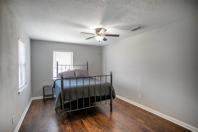 bedroom with ceiling fan, dark wood-type flooring, visible vents, and baseboards