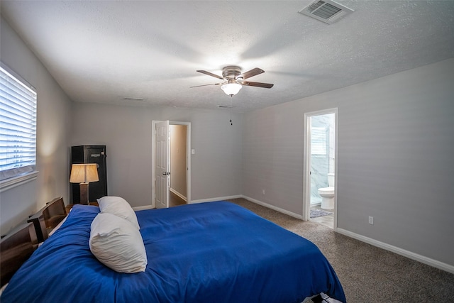 bedroom with a textured ceiling, carpet flooring, visible vents, baseboards, and ensuite bath