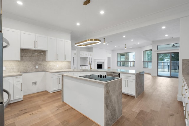 kitchen with a peninsula, white cabinets, open floor plan, light wood-type flooring, and a center island