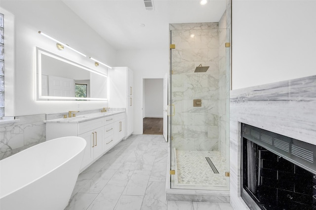 full bathroom with a fireplace, vanity, a freestanding bath, marble finish floor, and a marble finish shower