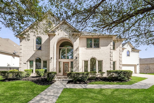 view of front of property with an attached garage, driveway, a front lawn, and brick siding