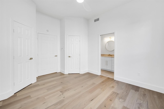 unfurnished bedroom featuring visible vents, ensuite bath, light wood-style flooring, and baseboards