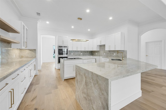 kitchen with open shelves, light wood-style flooring, white cabinets, a sink, and light stone countertops