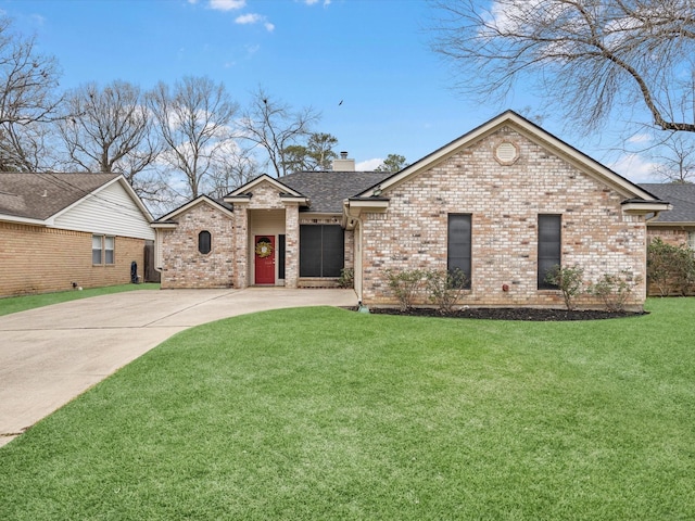 view of front of house with concrete driveway, brick siding, a chimney, and a front lawn