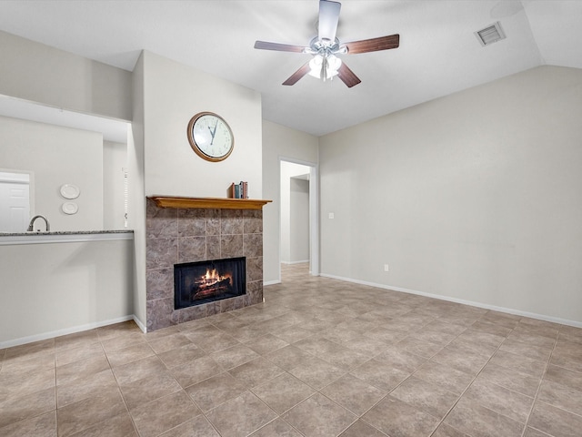 unfurnished living room featuring a ceiling fan, vaulted ceiling, a fireplace, and baseboards