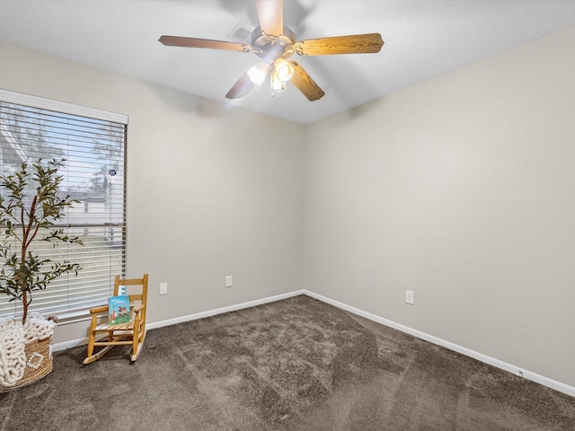 empty room with ceiling fan, dark colored carpet, and baseboards