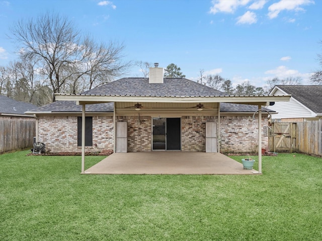 rear view of house with ceiling fan, a chimney, a fenced backyard, and a patio