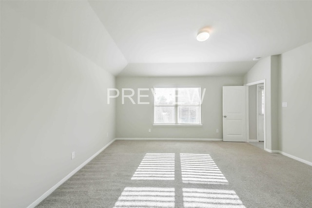 unfurnished room featuring light colored carpet, vaulted ceiling, and baseboards