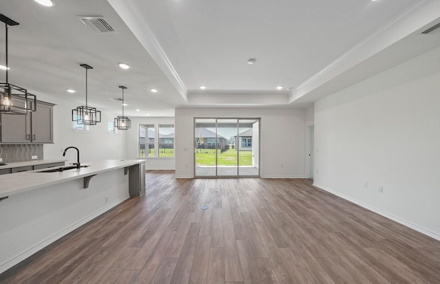 kitchen with a raised ceiling, light countertops, visible vents, open floor plan, and a sink